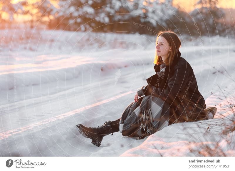 Young beautiful woman with short hair, in checkered scarf walking in snowy forest at sunset. Christmas holiday. Snow day fun winter people park nature lifestyle