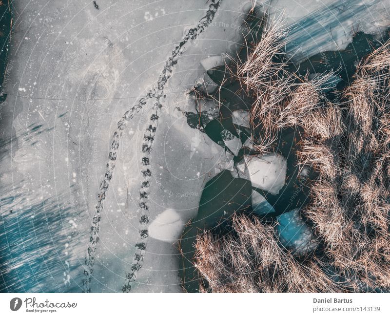 Panoramic aerial view of a frozen lake with animal tracks and cracked ice. Animal tracks on the frozen surface of the lake. Cracked ice on the lake background