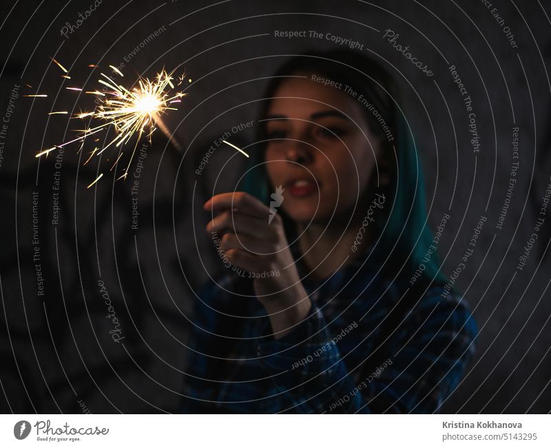 Portrait of model girl with blue hair looks with sparklers in their hands. Close up. Beautiful young teenage in city tunnel having fun with bengal fire. beach
