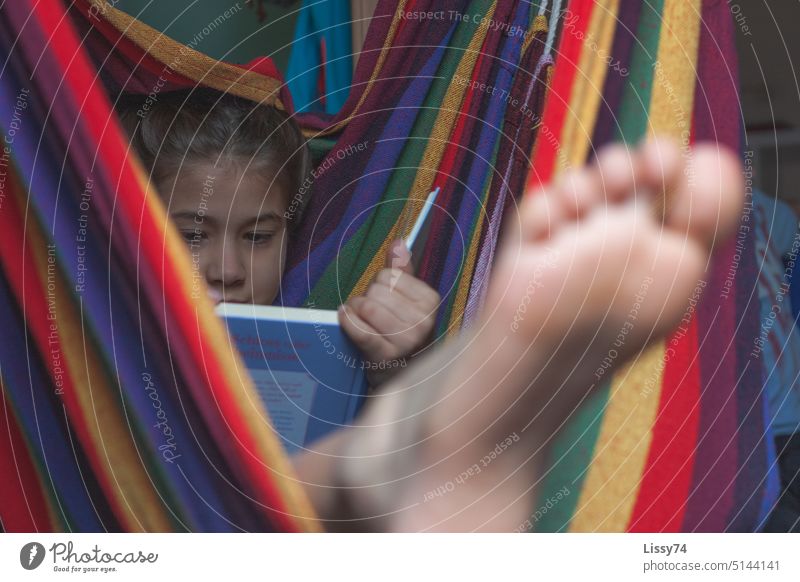 Reading girl deeply absorbed in a book, stretching her feet from a colorful striped hammock Child Girl Infancy Children's room Hammock variegated Book Feet