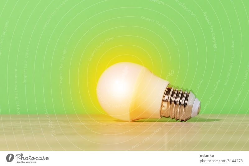 A glass white lamp shines with yellow light on a green background. New idea bulb energy innovation technology concept electricity invention power glasses