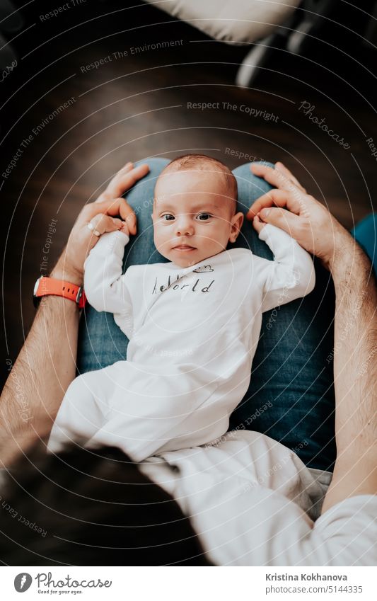 Portrait Of Cute Baby Boy Lying On Fathers Knees And Looking To Camera baby beautiful boy care caucasian cheerful child childhood comfort content cute face
