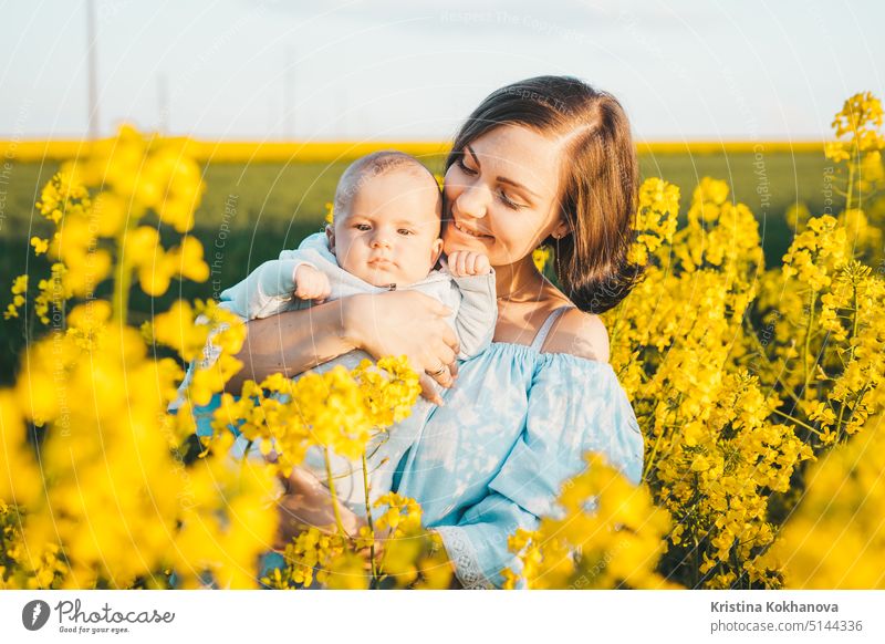 Young mother holding baby boy. Son having fun, smiling in yellow canola field. Love, family, joy concept person happiness child female nature happy woman summer