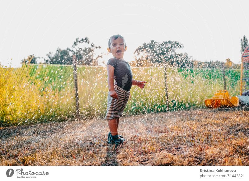 Happy adorable toddler boy having fun under rain. Baby laughs, he is very glad weather. person child outdoor playing drop childhood autumn day season happiness