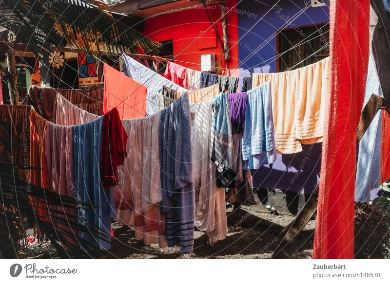 Colorful laundry in front of colorful walls on the clothesline Laundry variegated colored Wash leash Washing day Red Violet Sun Shadow housekeeping Pure neat