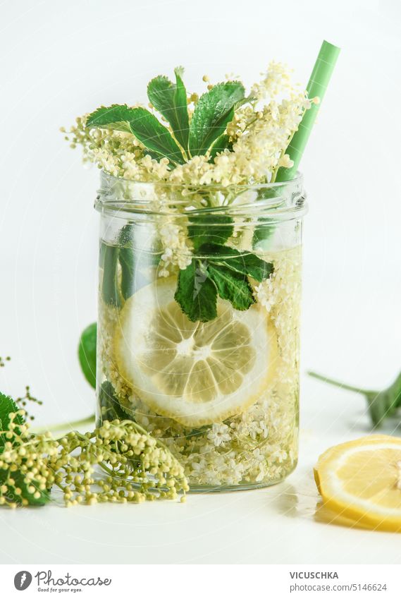 Healthy elderflowers lemonade in glass jar with lemon at white background healthy elder flowers infused water green ingredient refreshment natural yellow