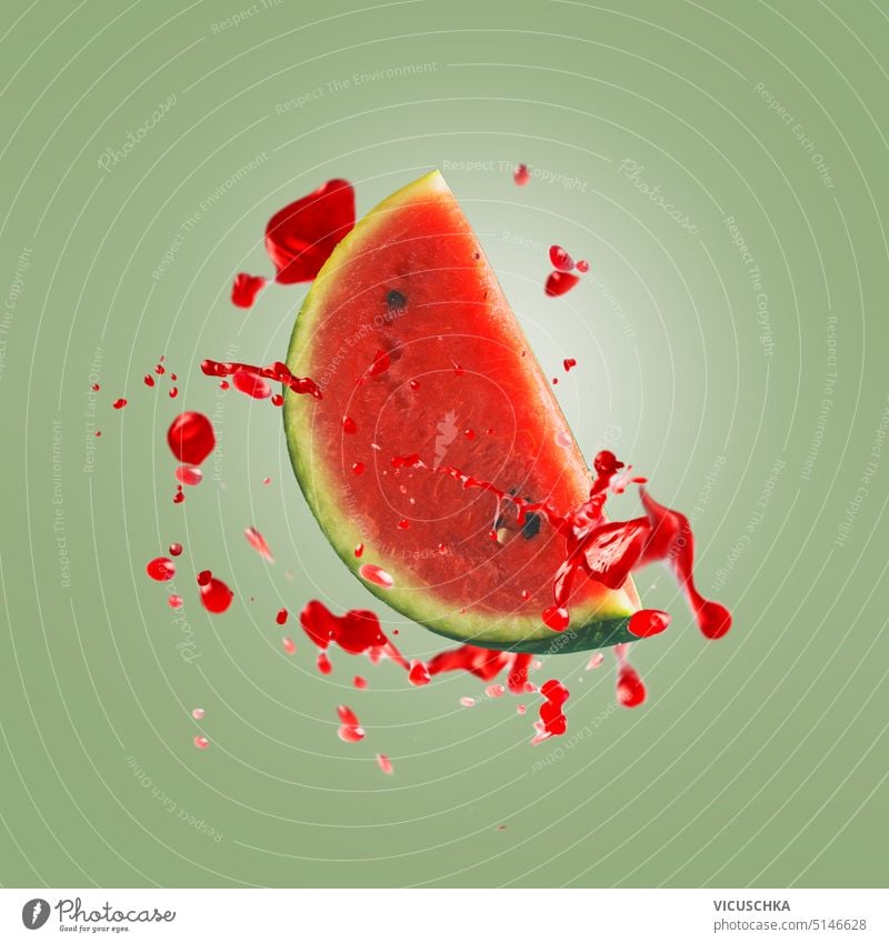 Flying watermelon slice with red juice plashing and drops at green background flying splashing piece object fruit summer healthy juicy fresh sweet levitation