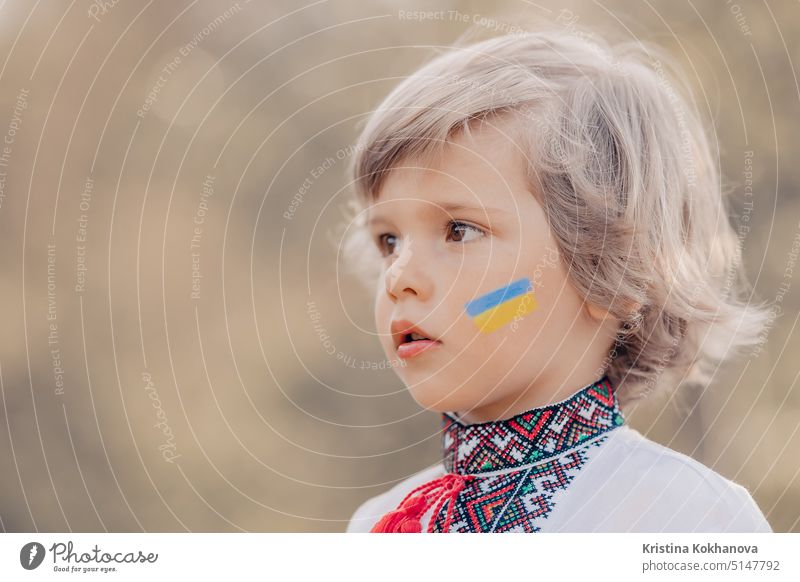Portrait of little ukrainian boy with blue yellow flag art on cheek. Child in traditional embroidery vyshyvanka shirt. Ukraine, freedom, national costume, victory in war. Copy space