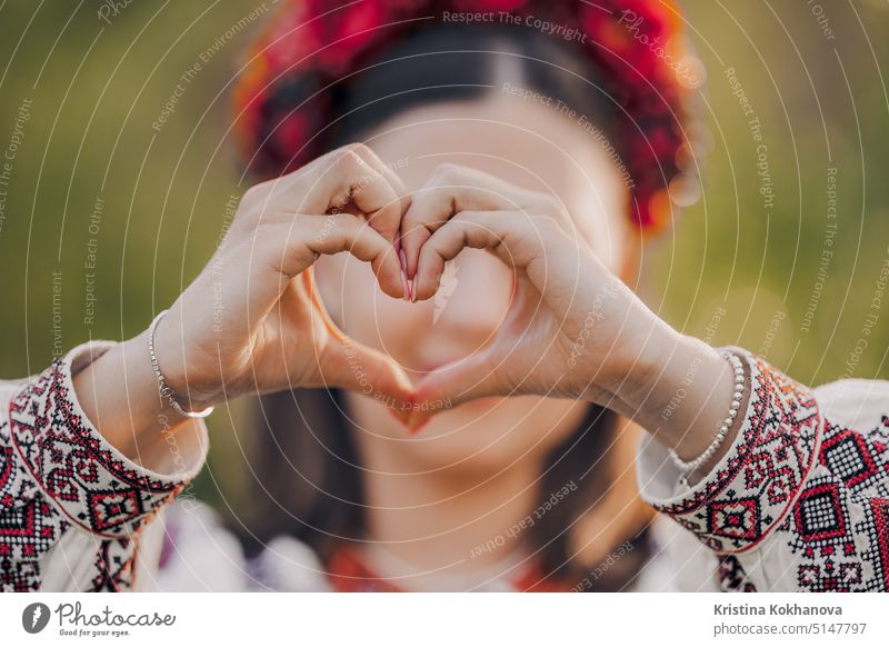 Ukrainian woman in traditional embroidery vyshyvanka dress making sign of shape heart. Ukraine, volunteering, donation help and love concept. beautiful girl