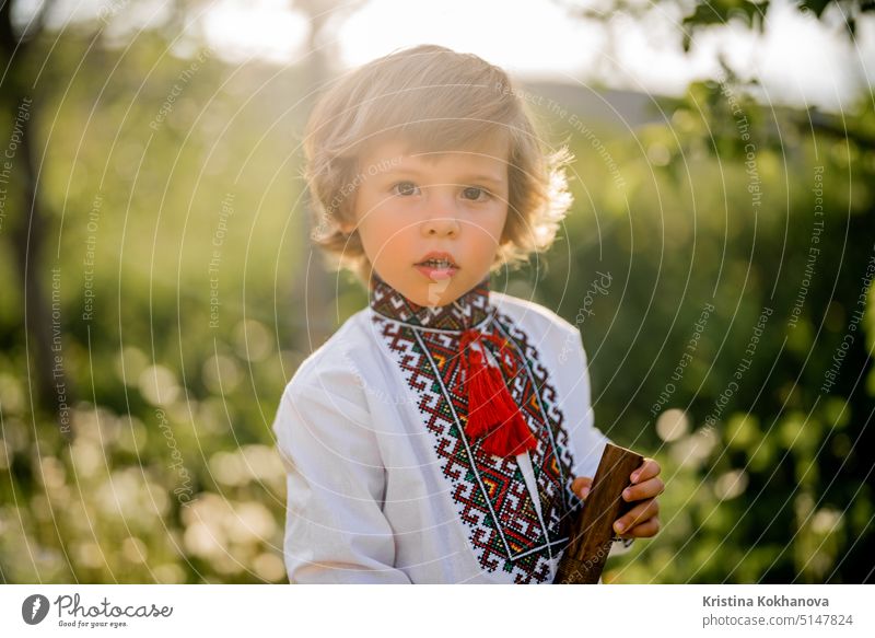 Portrait of little boy with woodwind wooden flute - ukrainian sopilka. Folk music concept. Musical instrument. Child in traditional embroidered shirt - Vyshyvanka.