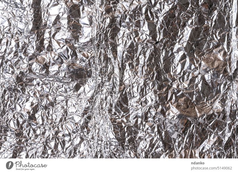 Crumpled sheet of gray foil, packaging material aluminum glossy wrapper wrinkled backdrop grey industrial leaf metallic nobody package piece ragged rough shine