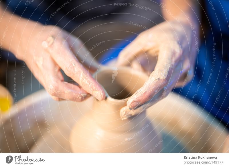 Working process of man's work at potters wheel in art studio. Unknown craftsman creates jug. Focus on hands only. Small business, talent, invention, inspiration concept