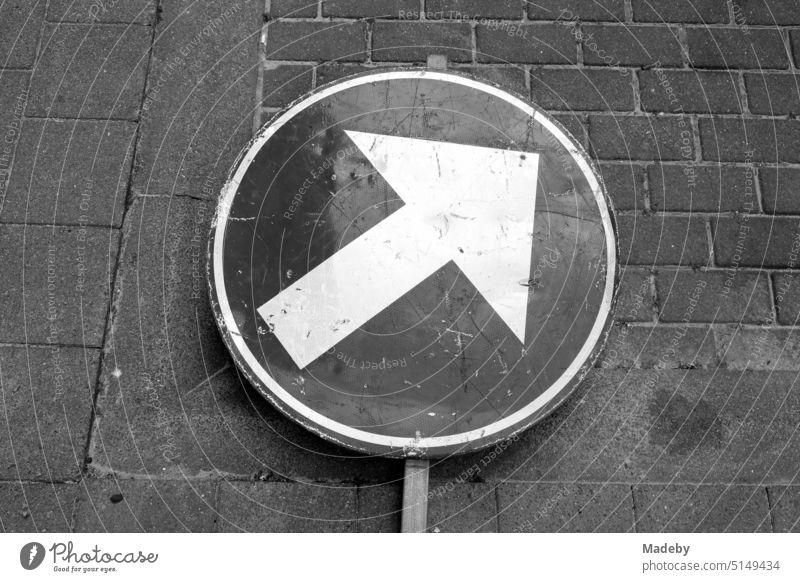 Overturned traffic sign with arrow on the sidewalk at a construction site in Knokke-Heist on the North Sea in West Flanders in Belgium in classic black and white