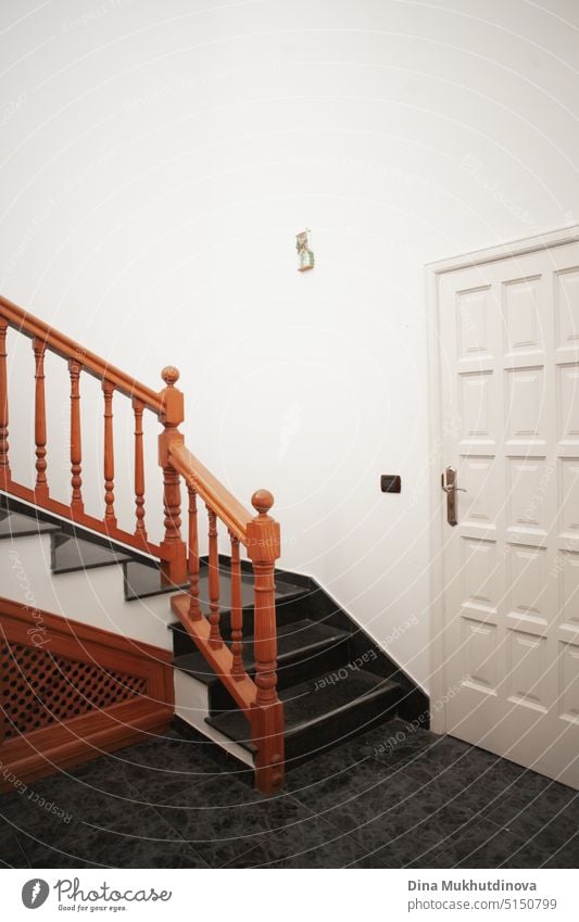 A wooden staircase at home vertical interior background. Minimal interior design with a white door and brown stairs with copy space. apartment minimal light