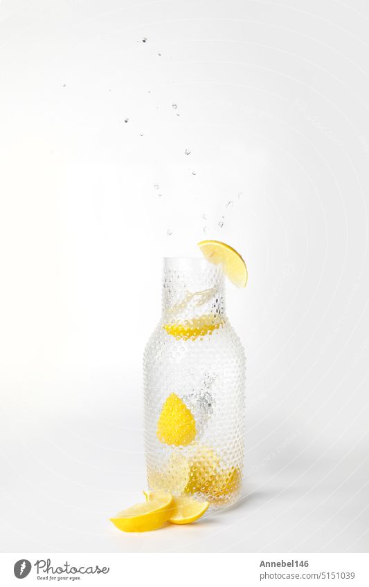 Glass of lemonade with splashing water on white background citrus slice fruit liquid drink isolated fresh healthy falling drop juice motion food yellow nature