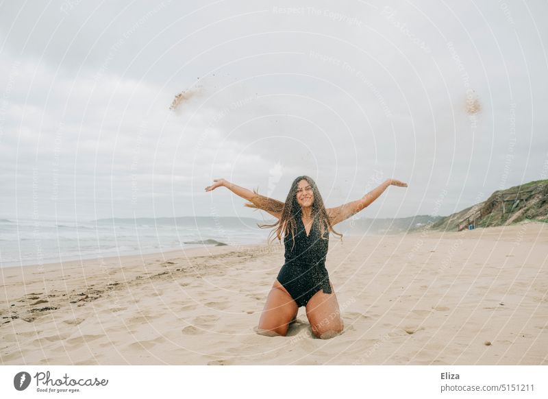 Woman in swimsuit throwing sand on beach Beach Sand Throw Joy vacation Swimsuit Vacation & Travel Ocean Young woman coast cloudy Human being Nature Exuberance