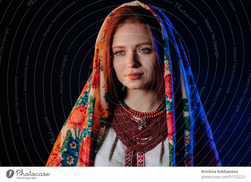 Charming ginger woman in traditional ukrainian handkerchief, necklace and embroidered blouse at black background. Ukraine, style, folk, ethnic culture.