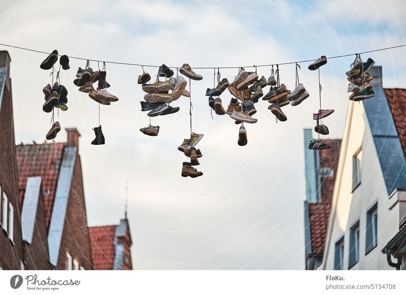 Shoes hanging on a leash Footwear Town Facade roofs Air height String Pair of shoes Colour photo Exterior shot Day Old Architecture Old town Building Recycling