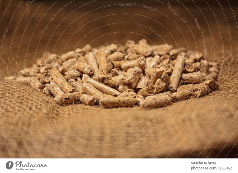 Close-up of wood pellets shows the glossy, closed surfaces and concave faces of the wood pellets on coarse jute fabric Wood pellets Sustainability