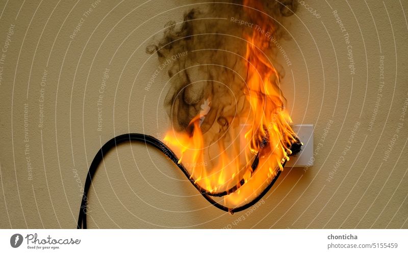 On fire electric wire plug Receptacle on the concrete wall background flame outlet receptacle socket afire aflame ablaze light shock power cable electrical