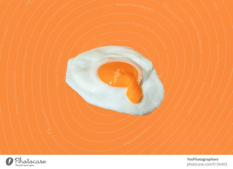Fried egg minimalist on an orange background with egg yolk dripping abstract breakfast bright close-up color concept cooking copy space creative cuisine cut out