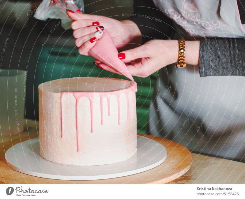 Unrecognisable woman decorating mousse glaze cake with rose, macarons decoration 30s baking caucasian celebration closeup detail icing kitchen party white