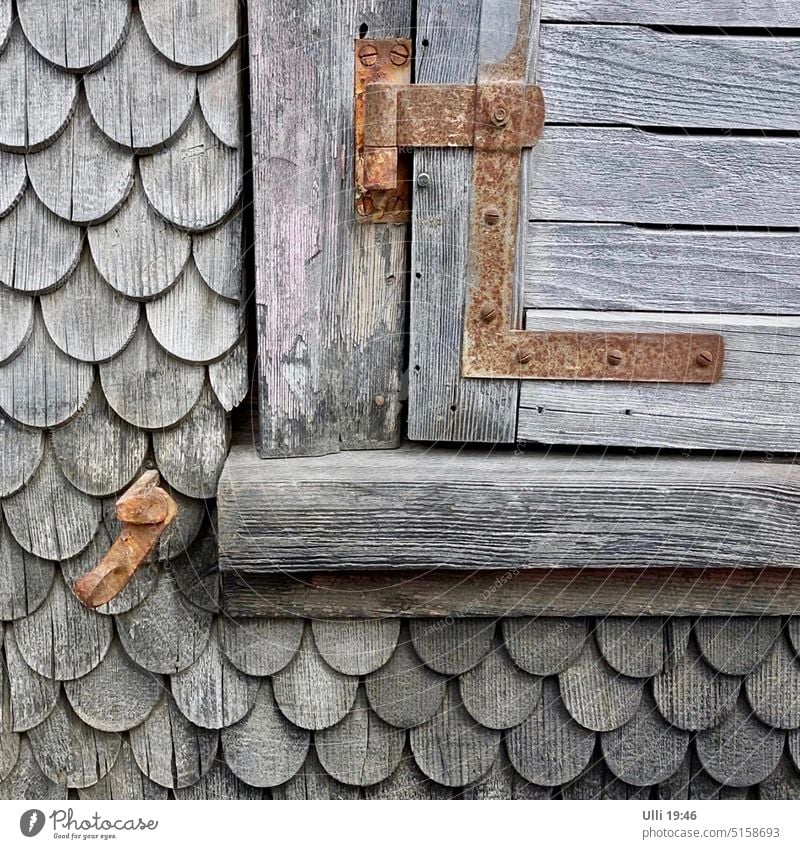 Old, scaly house wall with shuttered window flap. Wooden house Past Wood tiles Exterior shot Deserted Hut Wooden hut Window Hinge Facade Gray Day Window frame