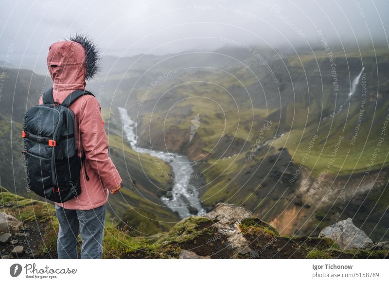 Woman wearing lilac jacket with backpack enjoying icelandic highland and river fossa close to Haifoss waterfall in Iceland woman haifoss tourist travel