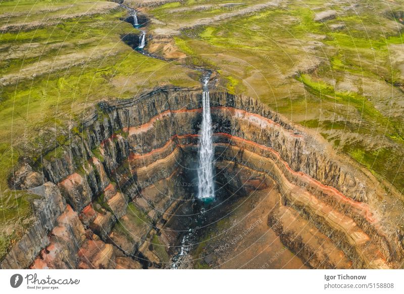 Aerial view of the Hengifoss waterfall in East Iceland. Hengifoss is the third highest waterfall in Iceland and is surrounded by basaltic strata with red layers of clay between the basaltic layers