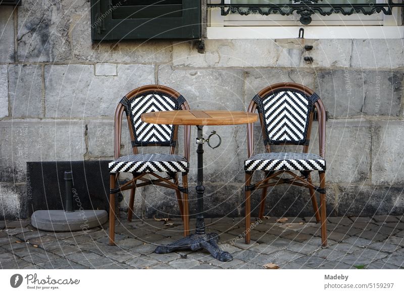 Round bistro table with bistro chairs in front of white window with shutters of a cafe and bistro in Boschstraat of the old town of Maastricht on the Meuse river in the province of Limburg of the Netherlands
