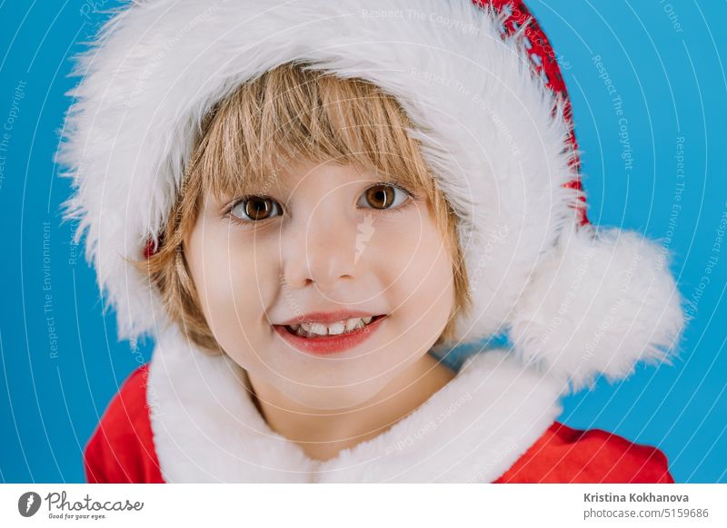 Portrait of adorable boy in Santa Claus hat on blue studio background. Christmas 4 years old artificial beard baby baby santa celebrate celebration cheerful