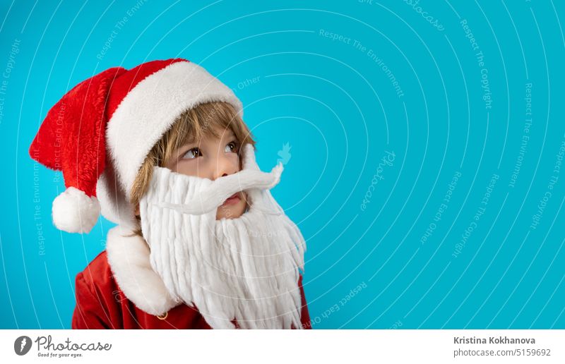 Portrait of adorable boy in Santa Claus hat and beard on blue. Christmas banner 4 years old artificial beard baby baby santa celebrate celebration cheerful