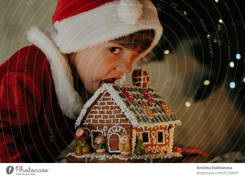 Cute little boy in Santa Claus costume eating gingerbread house, Christmas 4 years old adorable artificial beard baby baby santa celebrate celebration cheerful
