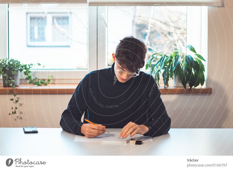Brown-haired young architect creates new product designs for a new futuristic world. Working with your own creativity. Compass, pencil, ruler and paper. Creative home office