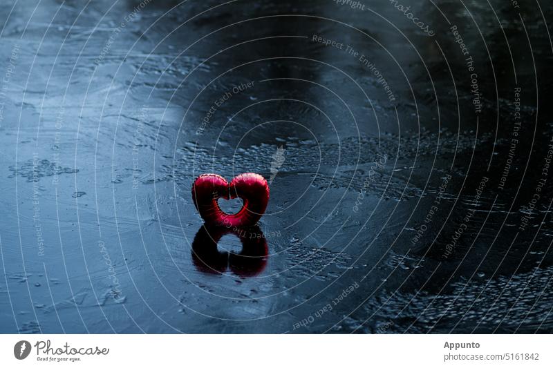 "Love trapped in ice" (A red heart-shaped balloon stands frozen in the wintry icy, blue-black shimmering surface of a lake). Red Heart Heart-shaped Balloon Ice