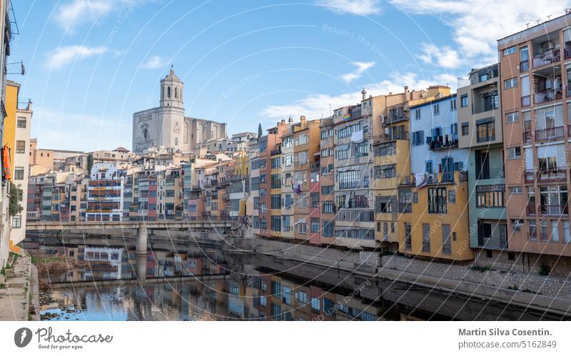 Colorful houses reflected in the Onyar river, in Girona, Catalonia, Spain. Church of Sant Feliu and Cathedral of Santa María in the background ancient