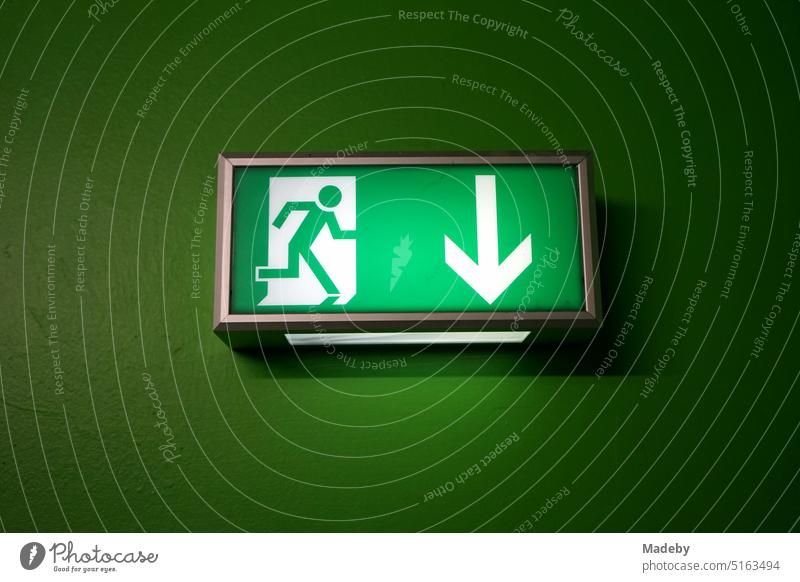 Pictogram with white arrow and green lighting on green wall indicating the escape route in the coal washing plant at the Unesco World Heritage Zollverein Coal Mine Industrial Complex in Essen, Germany, in the Ruhr region.