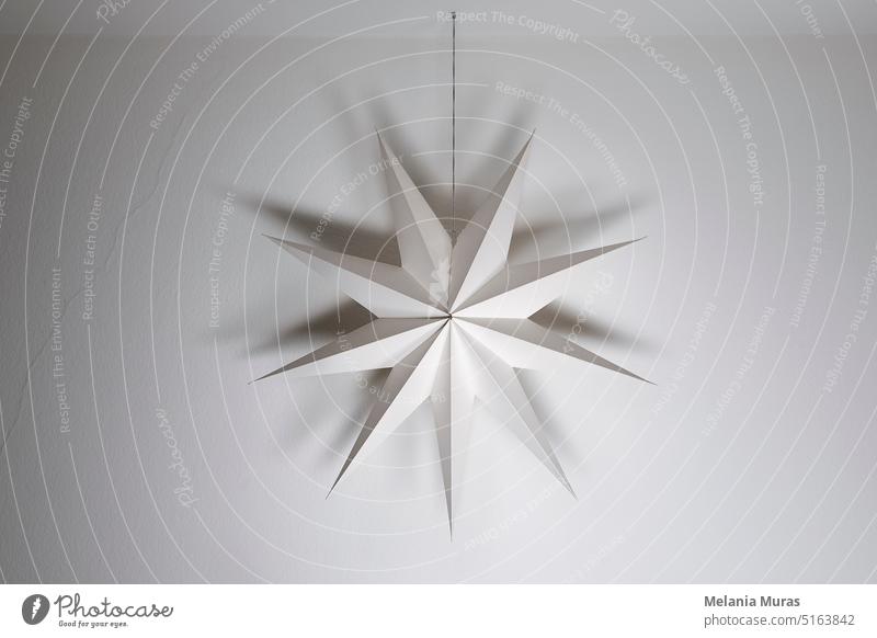 Cardboard paper star hanging on a white wall background. Simple nordic style home festive geometric decoration, christmas, winter time. abstract advent