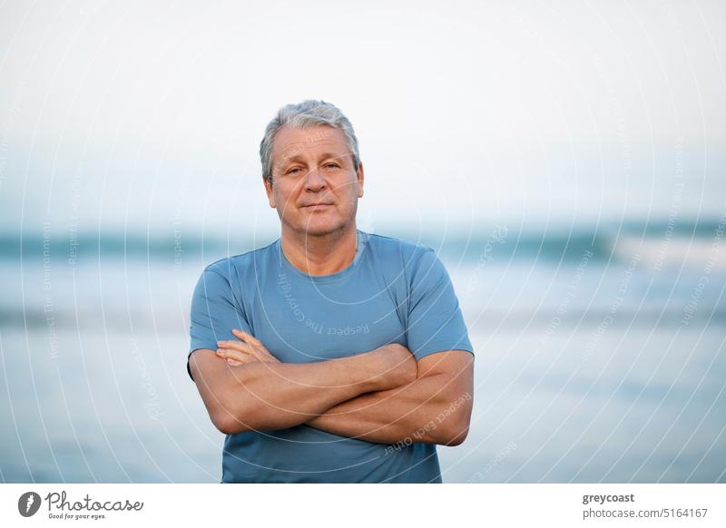 Portrait of a senior man on blurry sea background beach portrait retired retirement people male crossed arms elderly mature coast water folded arms shore ocean