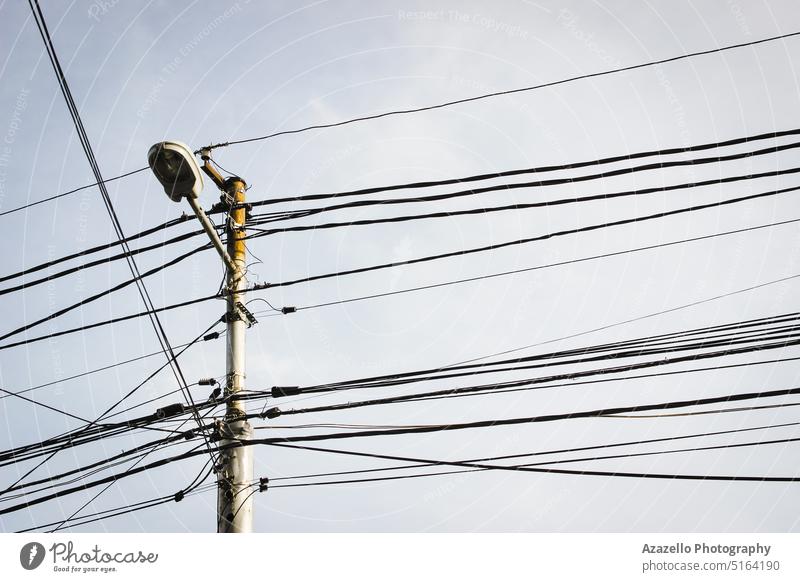 Electricity pylon with street lamp and many cables. electricity pylon danger current business pillar post utility communication connection infrastructure metal