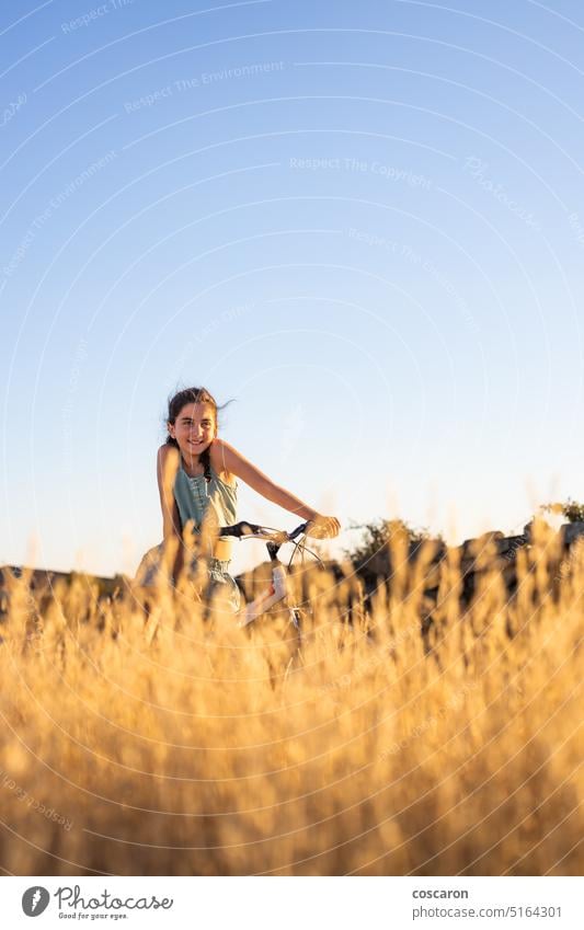 Cute girl with her bike at summer. active beauty bicycle biking blue sky caucasian child countryside cycling cyclist dry female field fit fun grass happiness