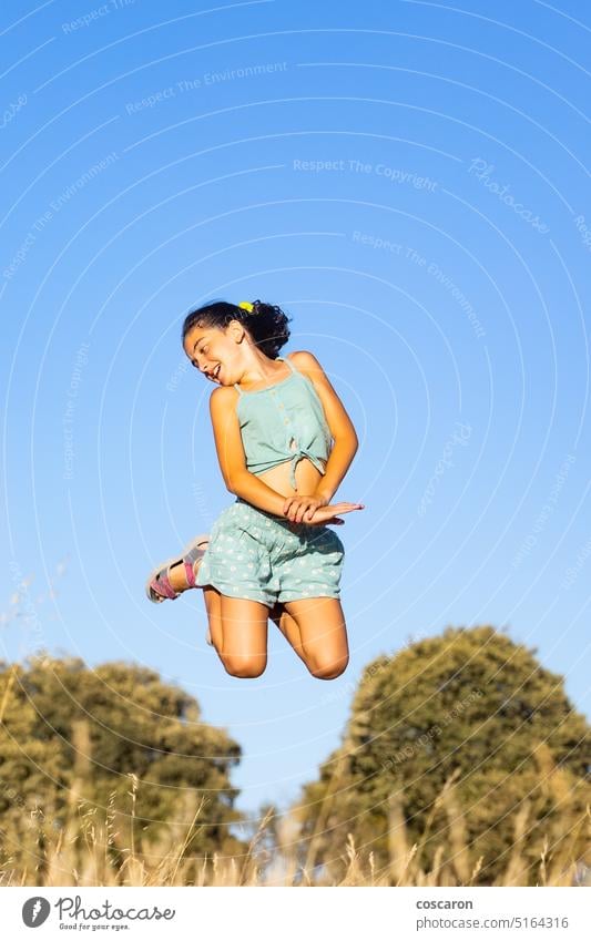 Funny girl jumping at summer against blue sky action active adolescent background beautiful bright carefree child childhood countryside energy enjoy enjoying