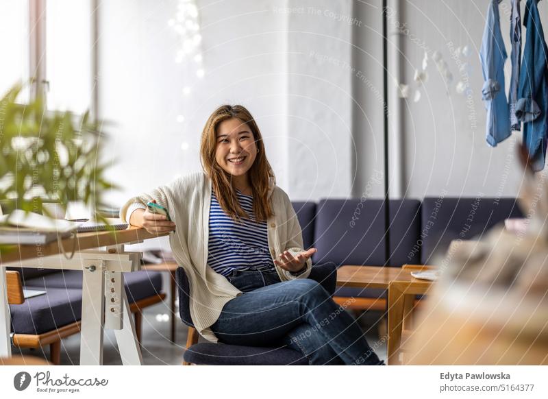 Portrait of a smiling creative woman sitting in a modern loft space real people millennials student indoors window natural girl adult one attractive successful