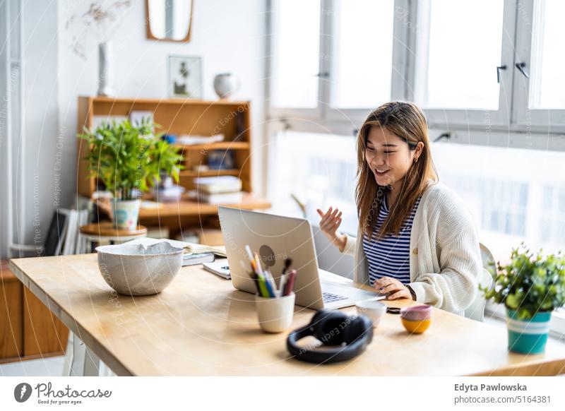 Young woman sitting at desk working on laptop real people millennials student indoors loft window natural girl adult one attractive successful confident person