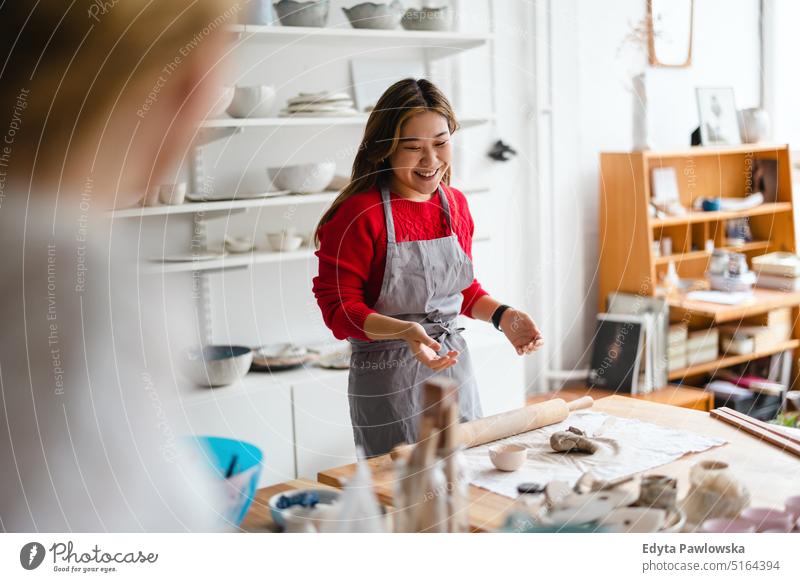 Young woman working in a pottery studio artist ceramics craft craftsperson hobbies workshop clay hand made professional freelancer creative startup business