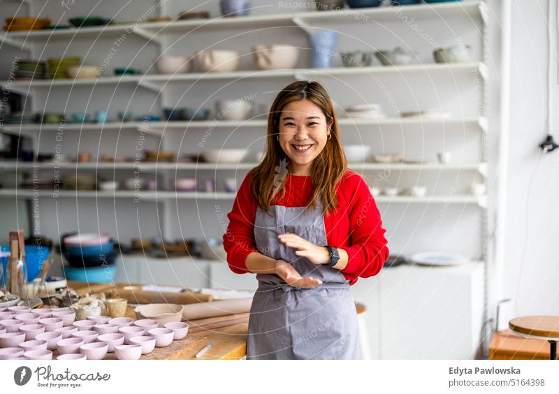 Young woman working in a pottery studio artist ceramics craft craftsperson hobbies workshop clay hand made professional freelancer creative startup business