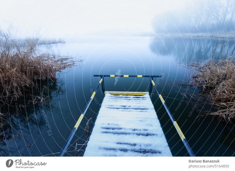 A pier with a handrail for disabled people on the shore of a lake on a foggy day person nature water railing landscape travel weather ramp design sky beach