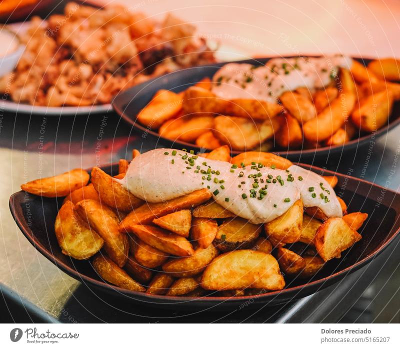Fried potatoes with sour cream sauce on a plate in a restaurant appetizer background baked brava bravas brave brave potatoes closeup cooking cuisine culture