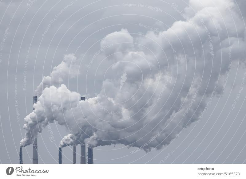Several chimneys of a coal power station release big clouds of smoke into the atmosphere, causing heavy industrial air and environmental contamination pollution
