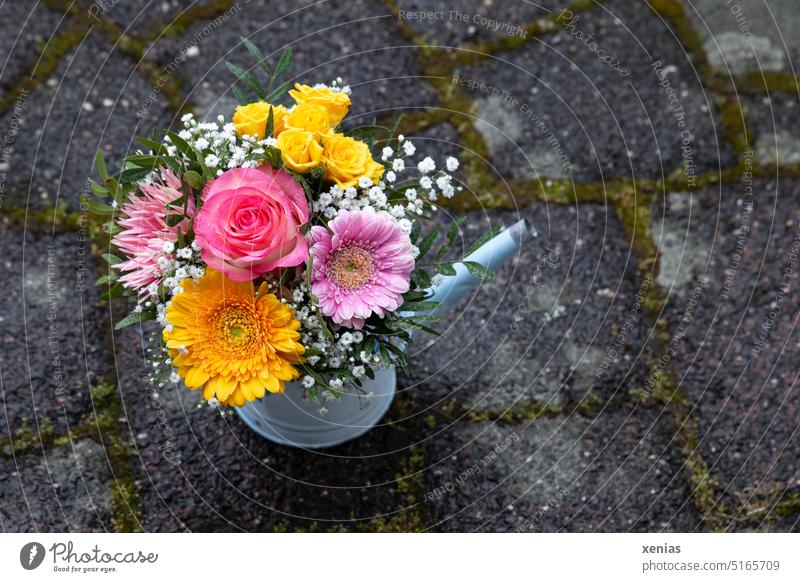 Bouquet: gerbera and roses in yellow and pink in light blue watering can stands on stone floor flowers Gerbera blossoms Floristry Watering can Yellow Pink Blue